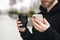 Reusable stylish bamboo cup and smartphone in the hands of a man, close-up.