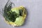 Reusable yellow mesh string bag with green vegetables on a gray concrete background. Plastic free concept, Top view, Copy space