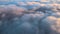 Reveal footage of aerial view from above at high altitude of dense puffy cumulus clouds flying in evening. Amazing