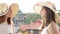 Revealing shot of two young women in large summer hats on the balcony