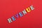 REVENUE word on red background composed from colorful abc alphabet block wooden letters, copy space for ad text