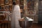 Reverend in white cassock praying in front of pulpit, icons and candles