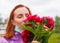 Revival after coronavirus. Redhead girl sniffs pink flowers with pulled down medicine mask. Recovery after flu