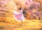 Revived porcelain doll in flying pink dress dancing in flowering spring forest, tender lady with dark hair in bright