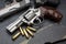 Revolver handguns and bullets on black stone background