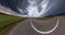 Revolves on road on road among fields with storm dark sky with gray clouds. Little planet Transformation with curvature of space.