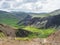 Reykjadalur valley with hot springs river, lush green grass meadow, rocks and hills with geothermal steam. South Iceland