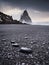 Reynisfjara, Iceland. A view of a popular spot in Iceland. Rocks during a storm. High waves. Pebbles on the seashore.