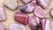 Rhodochrosite heap up jewel stones texture on light varnished wood background. Moving right seamless loop backdrop