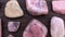 Rhodochrosite rare jewel stones texture on brown varnished wood background. Moving right seamless loop backdrop