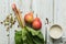 Rhubarb stalks and two pears on a white wooden background. A mug of sugar and a metal spoon lie nearby. Complementary