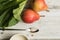 Rhubarb stalks and two pears on a white wooden background. A mug of sugar and a metal spoon lie nearby. Complementary colors