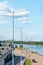 The rhythm of tall modern lampposts on the embankment of the river against the background of a blue sky with clouds