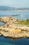 Rias Baixas seascape with Punta Cabalo lighthouse and mussel boat sailing between mussel beds called bateas. Galicia, Spain