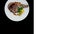 Rib-eye steak with corn rotating on a white plate. Top view, Isolated on the black background. Square layout for social