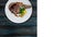 Rib-eye steak with corn rotating on a white plate. Top view on a wooden background. Square layout for social networks