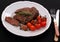 Rib eye steak, garlic, cherry tomatoes, herbs on black