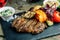 Rib eye steak with vegetables and peppers on a stone Board