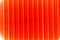 Ribbed wall of the shipping container. Red corrugated plastic tube background, closeup of photo.