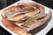 Ribs of tambaqui fish (Colossoma macropomum) on white square plate in close-up.