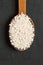 Rice Arborio in an wooden spoon on a black background