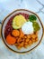 Rice with chicken in curry sauce and herbs on a plate with some fresh vegetables