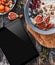 Rice coconut porridge with figs, berries, nuts, dried apricots and coconut milk in plate and tablet pc on rustic wooden background