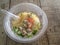 Rice congee mixed with shrimp, squid and pork in plastic bowl and spoon.