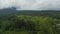 Rice fields and farm plantations on terraced hills in Bali. Descending aerial view of rural countryside below a cloudy