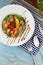 Rice noodles with salmon and spinach. Lunch in a white plate on the table. Tomatoes, lemon, fish, rosemary, soi and sesame seeds.