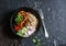 Rice noodles and teriyaki chicken stir fry with quick pickled cucumbers and radishes. On a dark background, top view.