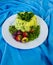 Rice salad. Decorated with olives and strawberries. On a blue fabric background