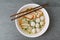 Rice stick noodles in broth with pork and meatballs in bowl on tile table