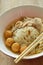 Rice vermicelli topping shrimp ball and slice boiled pork in soup eat by wooden chopstick