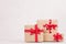 Rich bright gift boxes of kraft paper with red ribbons closeup on white wood table.