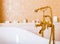 Rich gold faucet and white bath in the bathroom