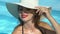 Rich woman in big white hat standing in pool, luxury resort hotel, wellness