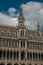 Richly decorated facade in Gothic style of Brussels City Museum and Belgian flag, at Grand Place.