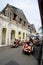 Rickshaw with passenger on street with old heritage building at background.