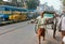 Rickshaw worker running on busy streets with rushing buses, cars, retro vehicles in indian city traffic jam