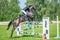 The rider on the bay show jumper horse overcome high obstacles in the arena for show jumping on background blue sky