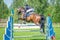The rider on the bay show jumper horse overcome high obstacles in the arena for show jumping on background blue sky
