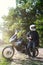 rider guy use smart phone in jeans biker jacket and helmet sit on tourist touring motorcycle. outdoors, dual sport adventure