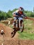 Rider on a low-power cross-country motorcycle, in sports equipment in flight after jumping on a springboard