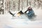 The rider making a turn drifting on a snowmobile on a deep snow surface outdoor on a background of snowy forest.