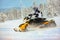 The rider making a turn drifting on a snowmobile on a deep snow surface outdoor on a background of snowy forest.