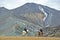 The rider rides on an Icelandic horse against a mountain landscape