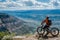 rider taking a break, bike propped against overlook with valley view