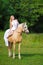 Rider woman blonde with long hair in a white dress with a train posing on a palamino horse