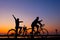 Riders cycling against sunset in silhouette with lots of negative space and dramatic sky